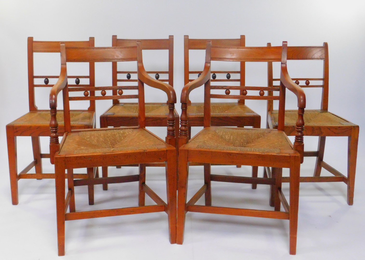 A set of six George III elm and rush seated country dining chairs, comprising pair of carvers and