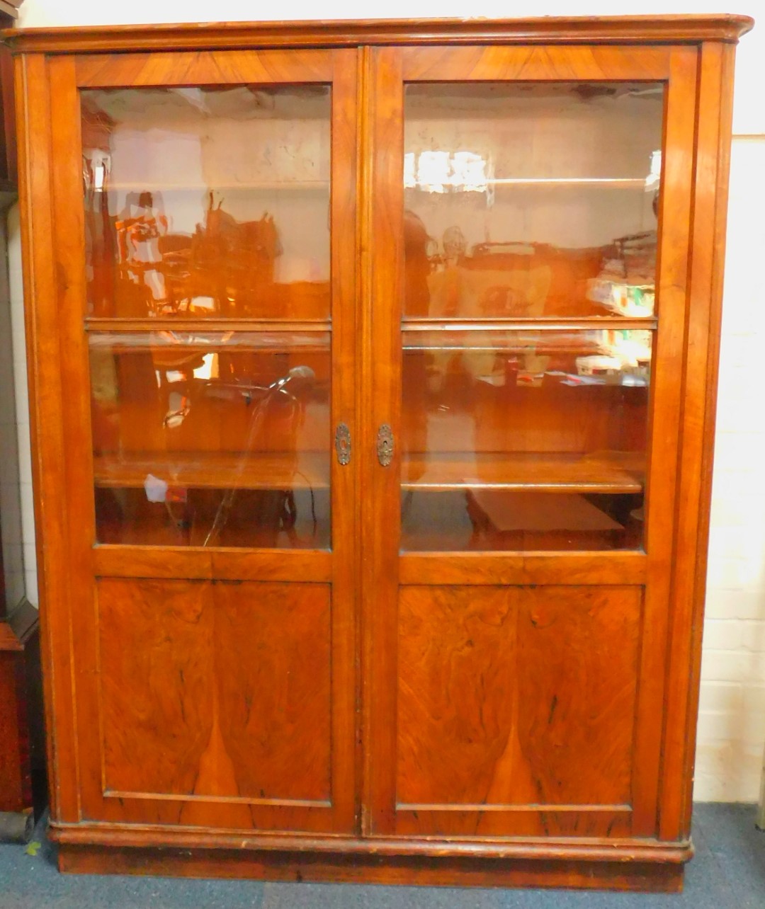 An early 20thC Continental walnut bookcase, with two glazed and panelled doors, opening to reveal