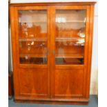 An early 20thC Continental walnut bookcase, with two glazed and panelled doors, opening to reveal