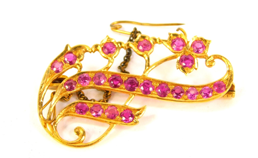 A floral scrolling brooch, with rubies set in a yellow metal mount, 4.5cm wide.