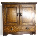 A 1920s/1930s oak wall cabinet, with two panelled doors, each with green Bakelite handles