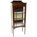 An Edwardian mahogany and boxwood strung display cabinet, the top with a shaped crest above a single