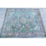 A large Chinese cut wool carpet, decorated with dragons, flowers, etc., on an olive green ground.,