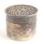 A small silver cylindrical pill box, the lid with a pierced Gothic decoration, on an ebonised