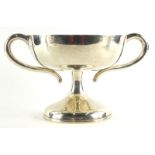 An Edwardian silver two handled cup, with shaped handles, waisted column, and domed foot,