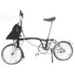 A Brompton black folding bicycle, with Marathon tyres, single bag etc.