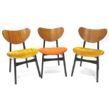 A set of three early G-Plan dining chairs, each with a heart shaped convex back, an ebonised frame