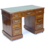 A late 19thC/early 20thC mahogany pedestal desk, the top with gadrooned leatherette inset above nine