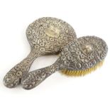 An Edwardian silver hand brush, embossed with flowers, scrolls and leaves, surrounding a vacant