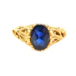 A sapphire set dress ring, with foliate carved shoulders and yellow metal shank, 2.7g all in.