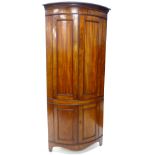 An early 19thC mahogany bow fronted standing corner cabinet, the top with a reeded and dentil