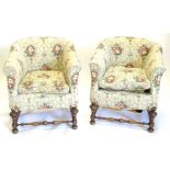 A pair of walnut tub shaped armchairs, upholstered in floral fabric, on part turned carved legs with