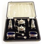 A George VI silver six piece cruet, comprising two mustard pods with covers and shaped legs, each