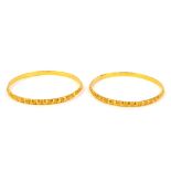 A pair of circular bangles, with faceted decoration, unhallmarked yellow metal.