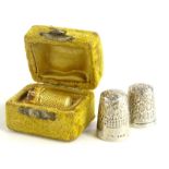 Three thimbles, comprising two silver floral thimbles, and a yellow metal cased thimble, unmarked (