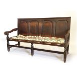 An 18thC oak quadruple panelled settle, with shaped arms, strung seat and part turned square section