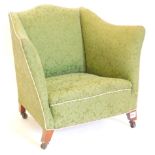 An early 20thC mahogany tub shaped arm chair, upholstered in green patterned damask, with