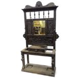 A late Victorian carved and ebonised oak hall stand, the raised back with a shaped pediment