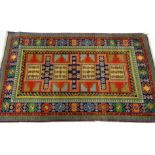 A Kazak type rug, with a central multicolour design with roundels, stars, latch hooks etc., one wide