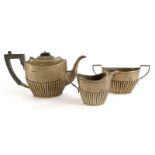 An Edwardian silver three piece tea set, with part fluted decoration, the teapot with ebonised