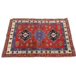 A Kazak type rug, with three brightly coloured medallions, on a red ground, embellished with