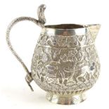 An eastern silver cream jug, with repousse decoration of elephants, palm trees, buildings, etc.,