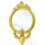 A late 19thC gilt gesso oval wall mirror, the elaborate frame decorated with flowers, grapes,