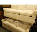 Two similar three seater sofas, each with cream loose covers.