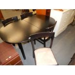 A black ash extending dining table and four chairs, the rectangular top with rounded corners on