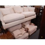 A George III style camel back sofa, upholstered in cream fabric and two similar armchairs, each with