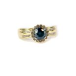 A 9ct gold and diamond ring, the central blue cut diamond in a surround of white diamonds, with