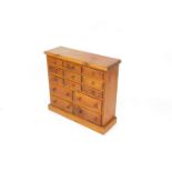 A pine table top chest, of nine short over four medium drawers, raised on a plinth base, 65cm