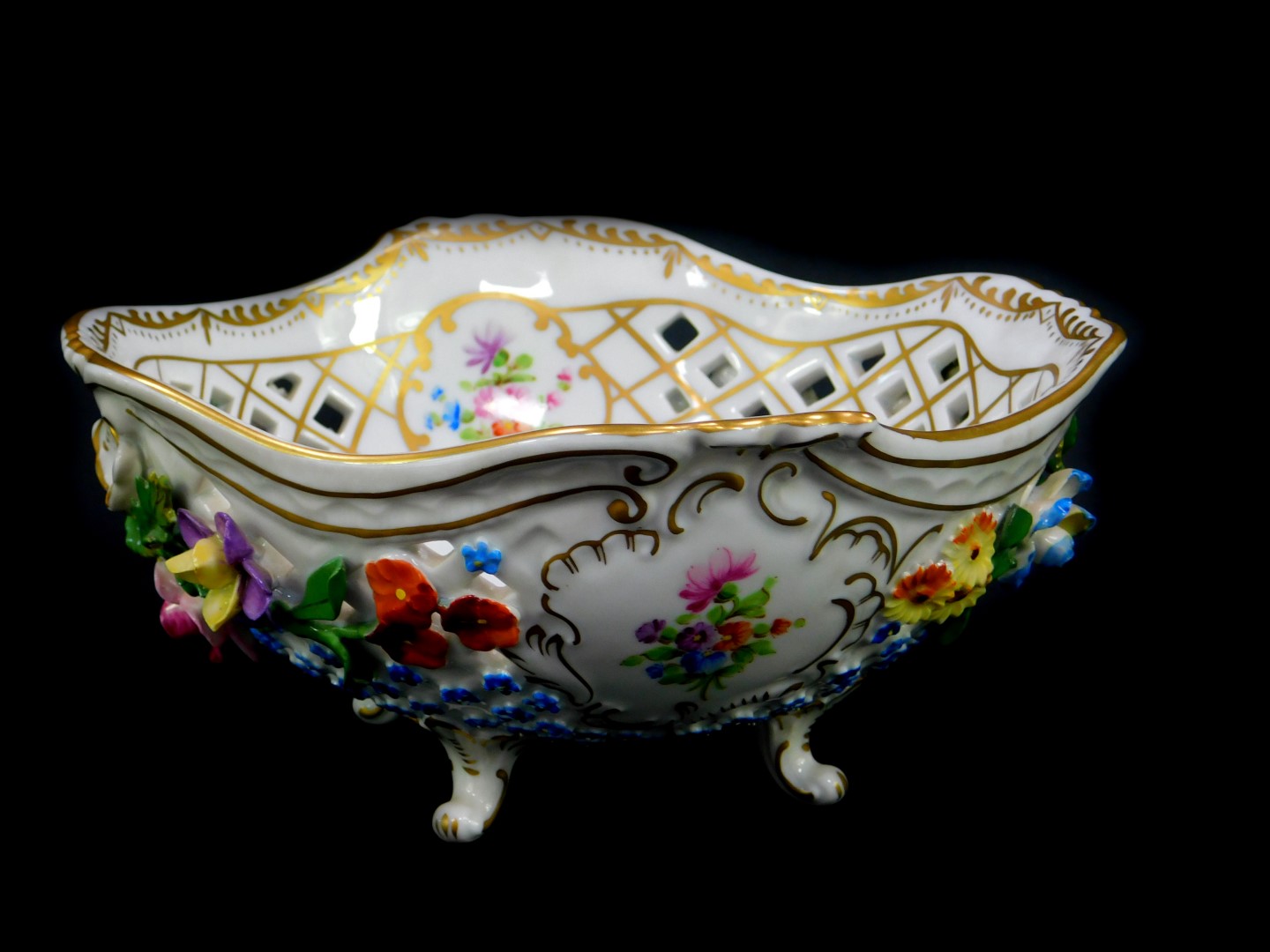 A 20thC Dresden porcelain bowl, of pierced form, encrusted and painted with flowers, raised on