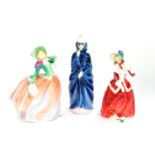 Three Royal Doulton figures, modelled as Christmas Morn HN1992, Masque HN2554, and Autumn Breezes