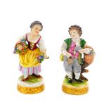 A pair of 20thC Volkstedt porcelain figures, of a boy with grapes and a girl with flowers, raised on