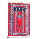 A modern Middle Eastern bordered prayer rug, with traditional designs in blue and pink on a red