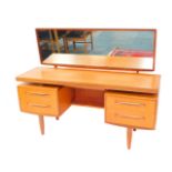 A G-Plan teak dressing table, with a rear attached rectangular swing frame mirror, above a central