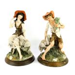 A pair of Capodimonte porcelain figures of a shepherd and shepherdess, monogrammed, raised on a