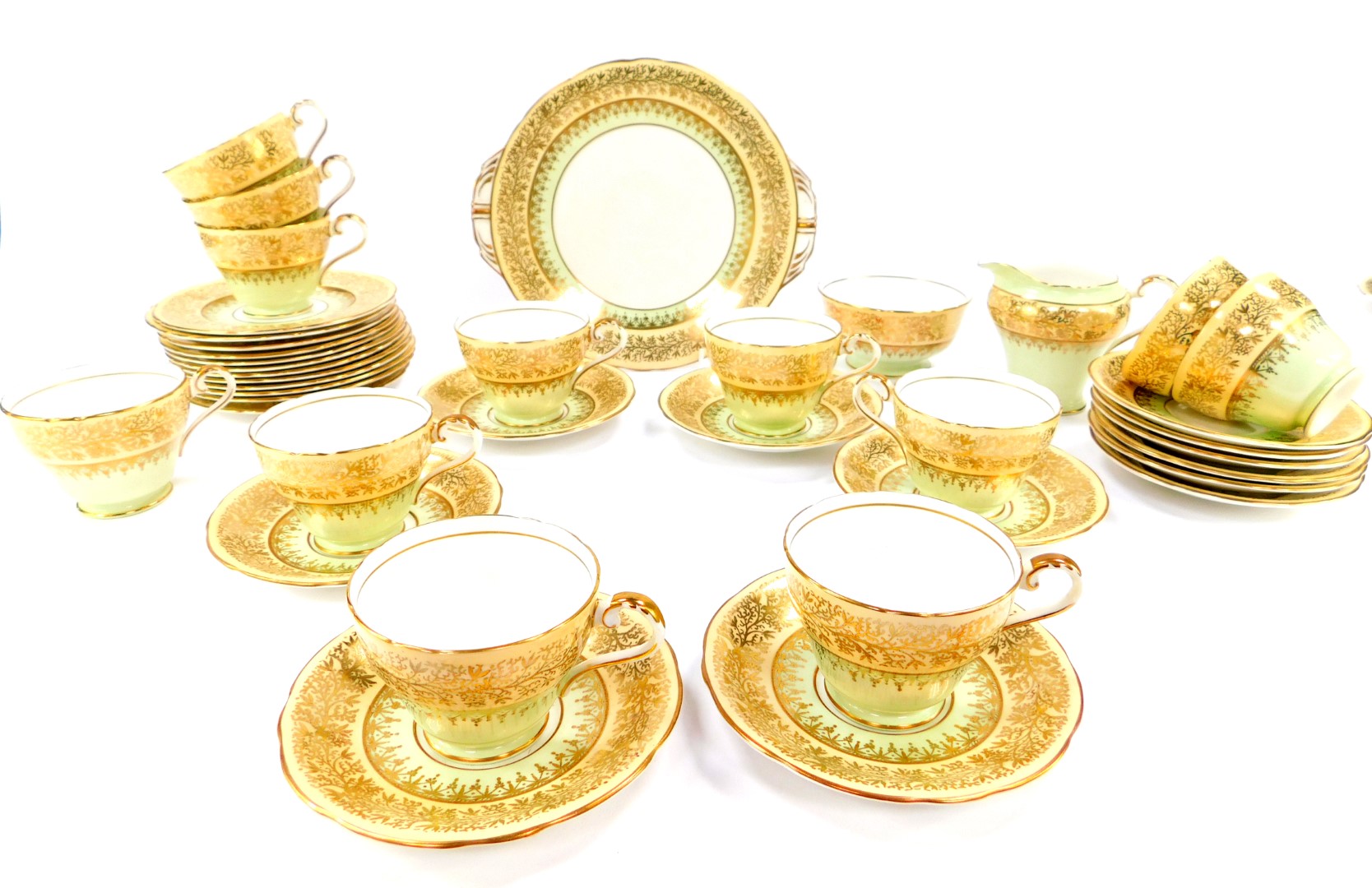 An Aynsley porcelain tea service, gilt decorated with mistletoe against a light green and peach