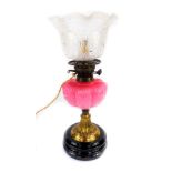 A Victorian brass oil lamp converted to electricity, with a pink fluted glass reservoir, moulded