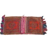 A Turkish Kelim red ground saddle bag, decorated with guls and geometric motifs, 132cm x 53cm.
