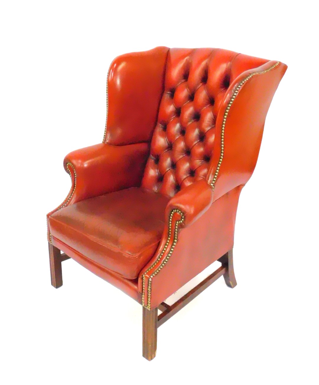 An oak framed red leather button back wing armchair, with loose cushion seat, and brass stud work,