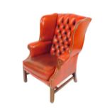 An oak framed red leather button back wing armchair, with loose cushion seat, and brass stud work,