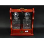 A mahogany two bottle tantalus, containing a pair of Royal Scot crystal decanters and stoppers, with