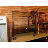 An early 20thC oak tea trolley, with glass shelves, lower drawer raised on brass castors, 70cm high,