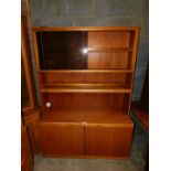 A late 20thC teak lounge unit, the top with glazed doors and shelves over a sideboard base, 171cm