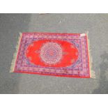 A modern silk rug, red ground with central circular medallion and repeating floral borders, 108cm