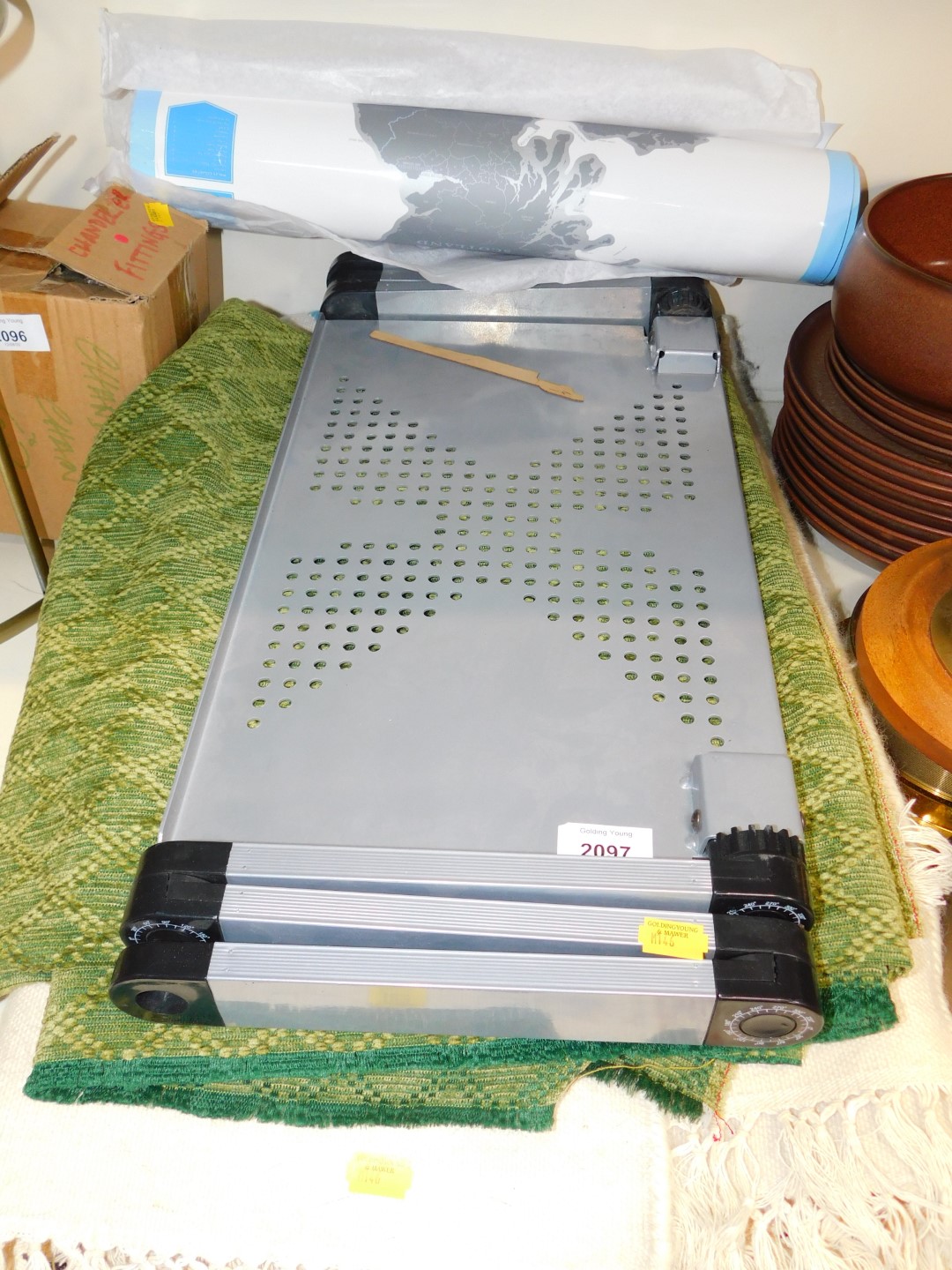 A floral cream ground rug, green table covering, folding table and a poster of the United Kingdom