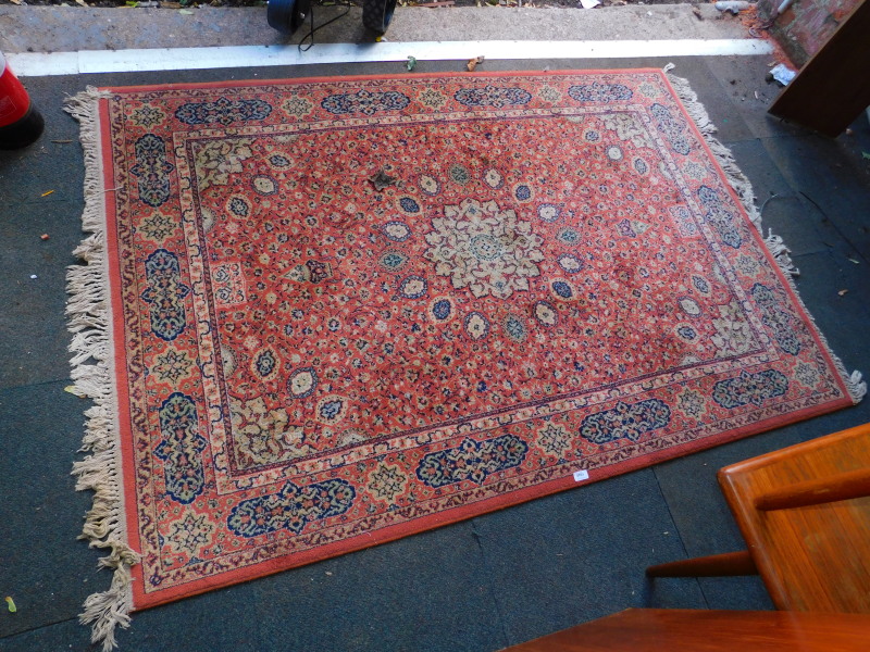 A machine made wool rug, Persian style decorated with central flower head medallion and repeating