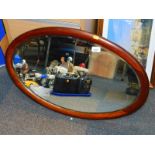 A mahogany oval framed mirror, inset with bevelled glass.